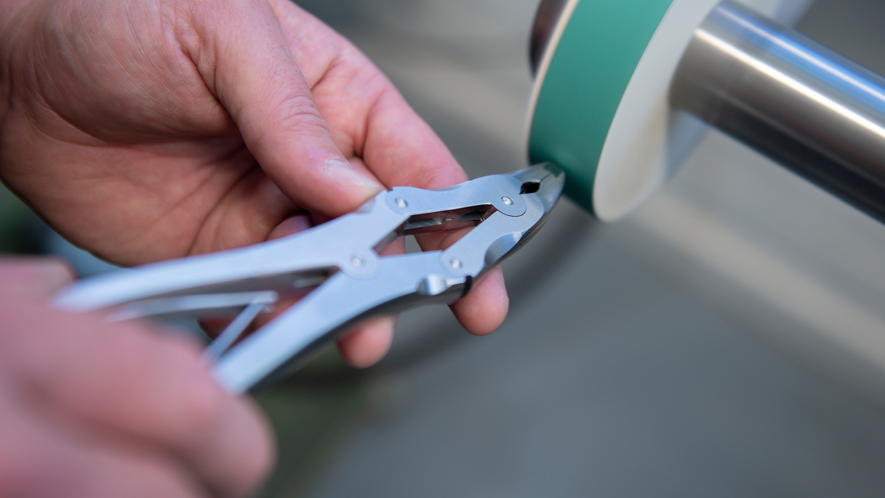 A set of surgical pliers being polished by a professional surgical repair tool.